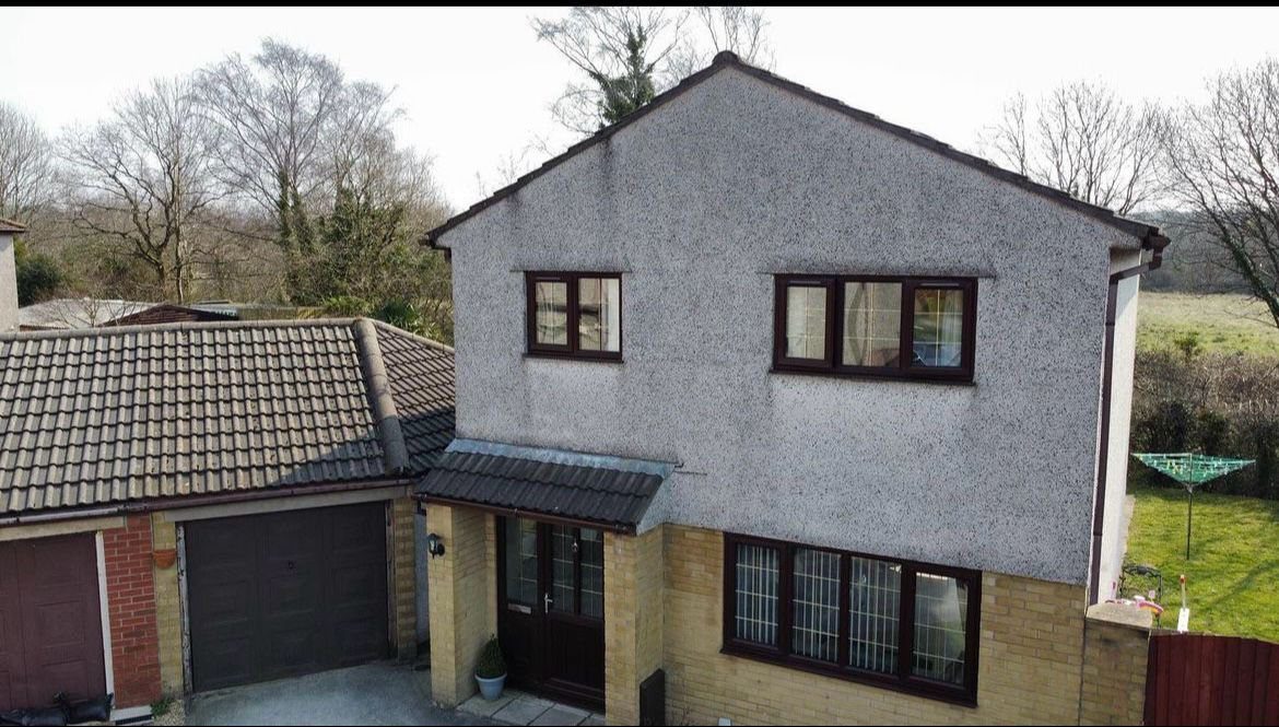 Weathered pebble dash on a detached house before repair